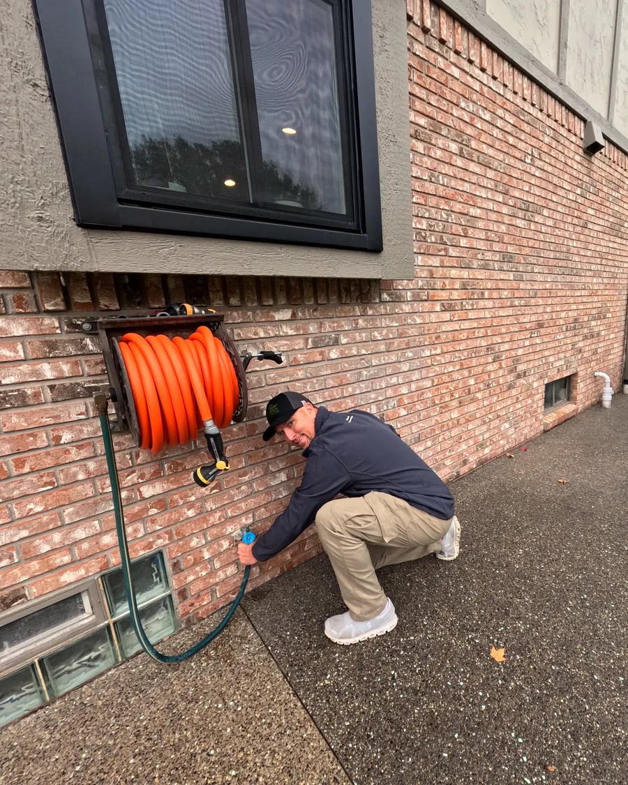 Kyle Winn of PreFlight Home Inspections disconnecting a garden hose from an outside spigot before winter